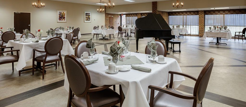 An elegant dining area with table settings and a grand piano.