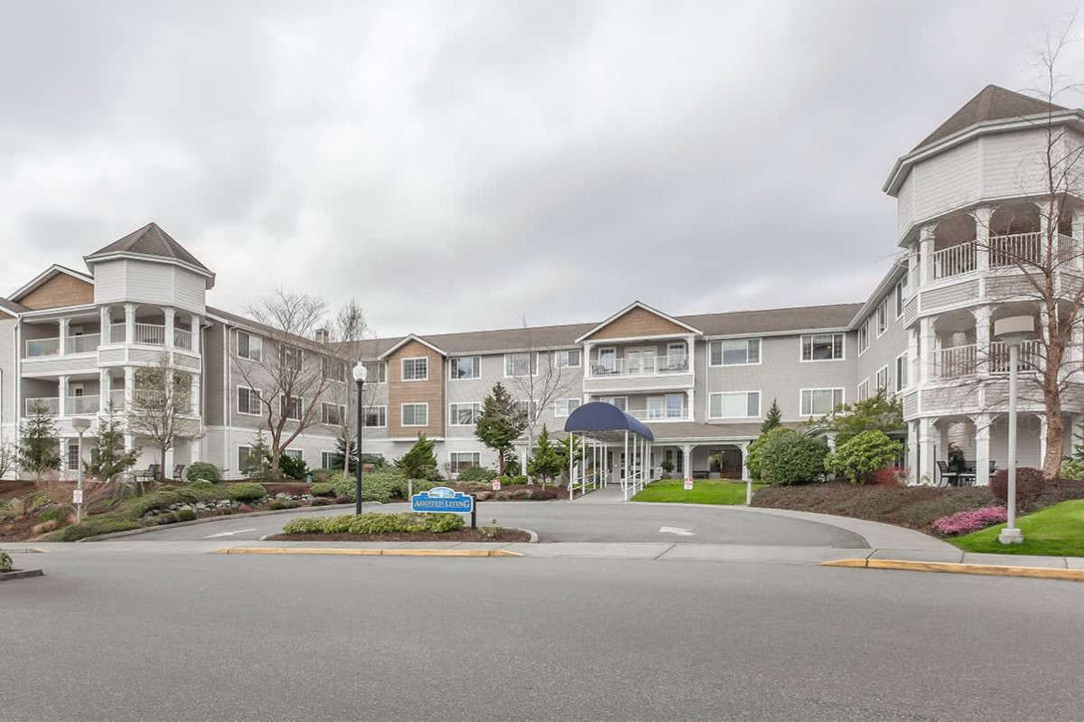 A residential apartment complex with a driveway and landscaped entrance.