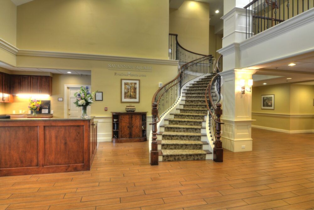 A spacious hotel lobby featuring a grand spiral staircase and a reception desk.