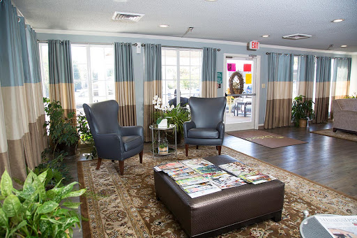A cozy lobby area featuring comfortable chairs, a coffee table with magazines, and large windows adorned with stylish curtains.