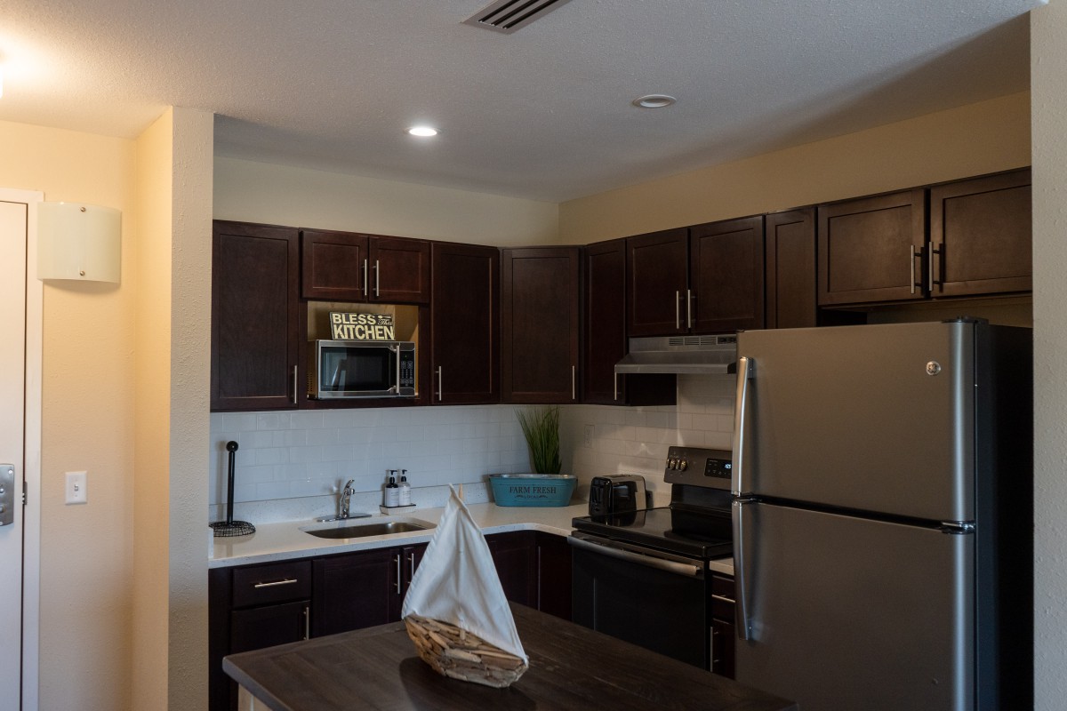 A modern kitchen with dark cabinets and stainless steel appliances.