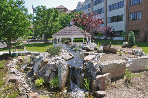 A serene outdoor space featuring a gazebo and a waterfall surrounded by lush greenery.