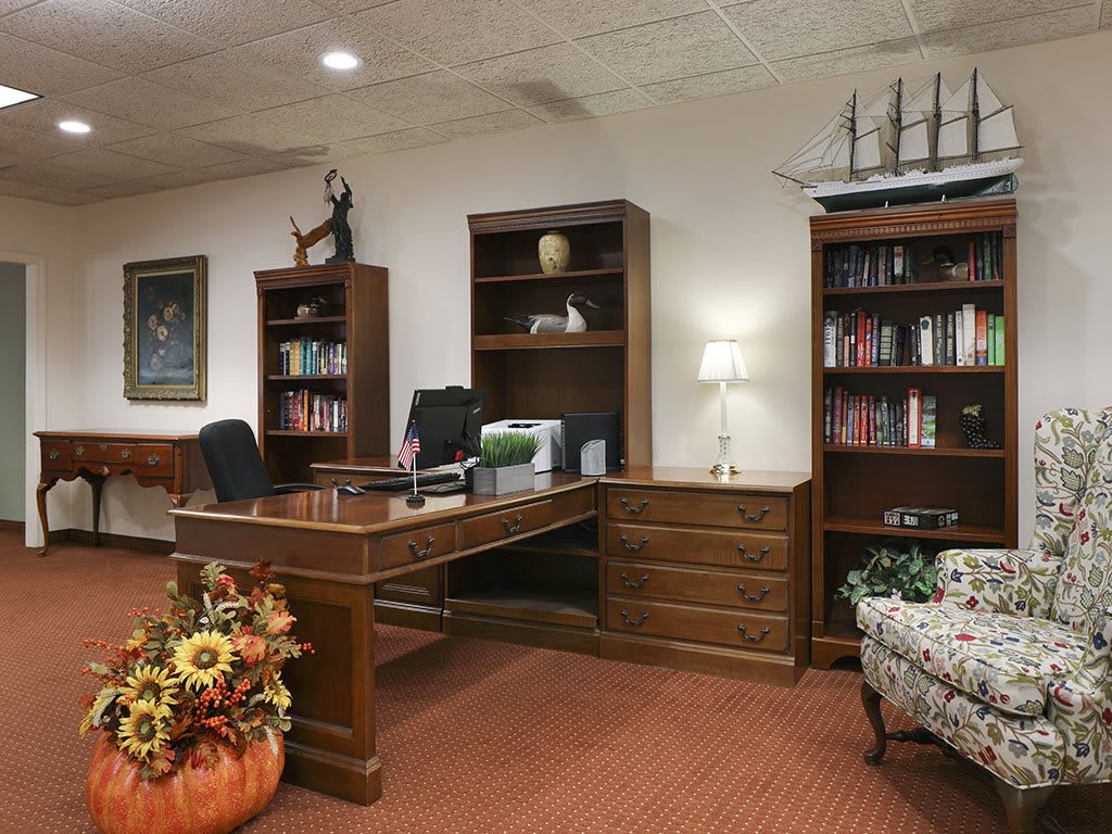 A cozy office space with a traditional wooden desk and shelves filled with books.