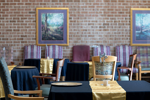 A beautifully arranged restaurant interior featuring tables draped in elegant fabrics and an artistic painting on the wall.