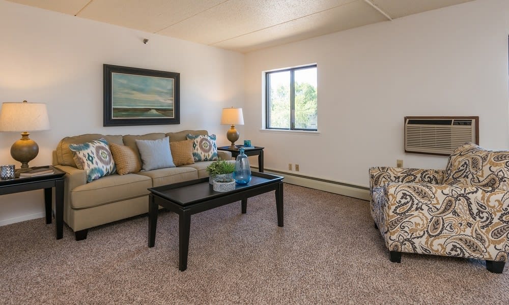 A cozy living room with a beige sofa, decorative pillows, and a black coffee table.