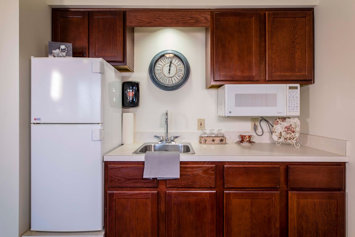 A cozy kitchen with wooden cabinets, a refrigerator, and a microwave.
