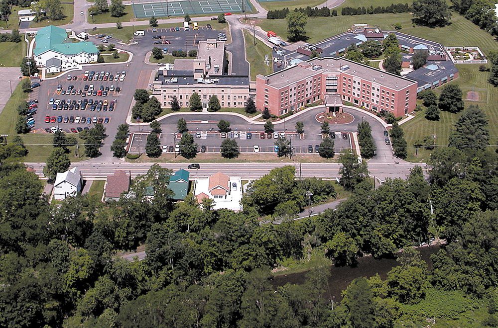 Aerial view of a large building complex with parking lots and surrounding greenery.