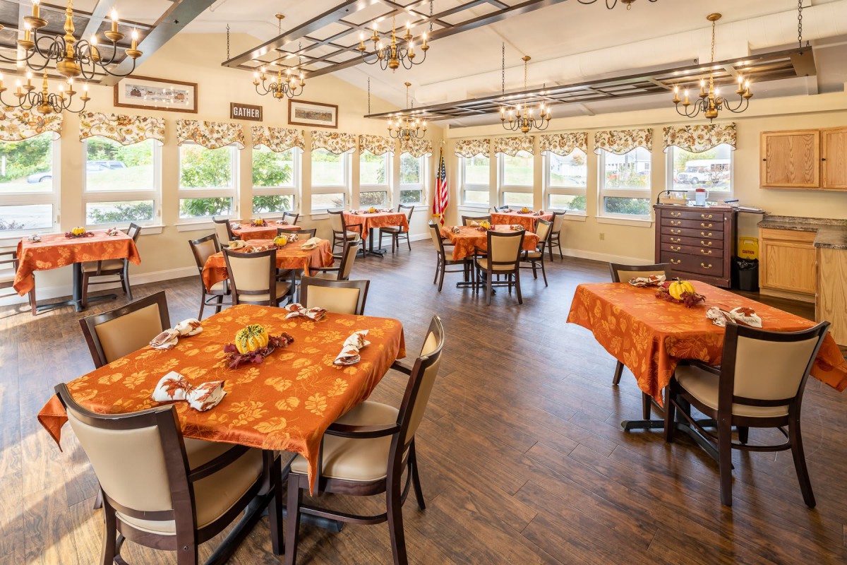A spacious dining area with beautifully set tables and elegant chandeliers.