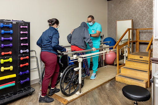 A physical therapy session where a patient is assisted to walk with support.