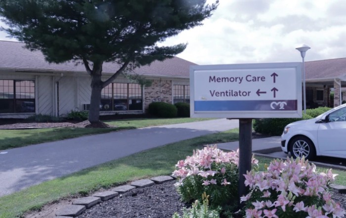 A sign outside a healthcare facility directing to memory care and ventilator units.