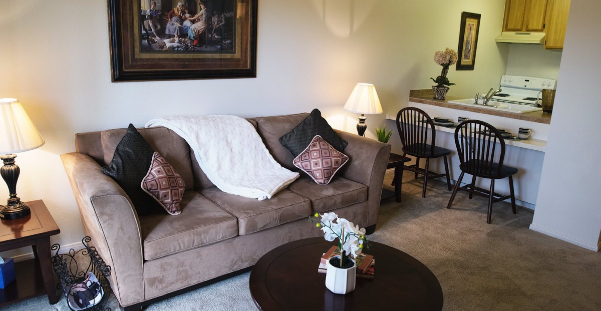 A cozy living room with a comfortable sofa, decorative pillows, a round coffee table, and warm lighting.