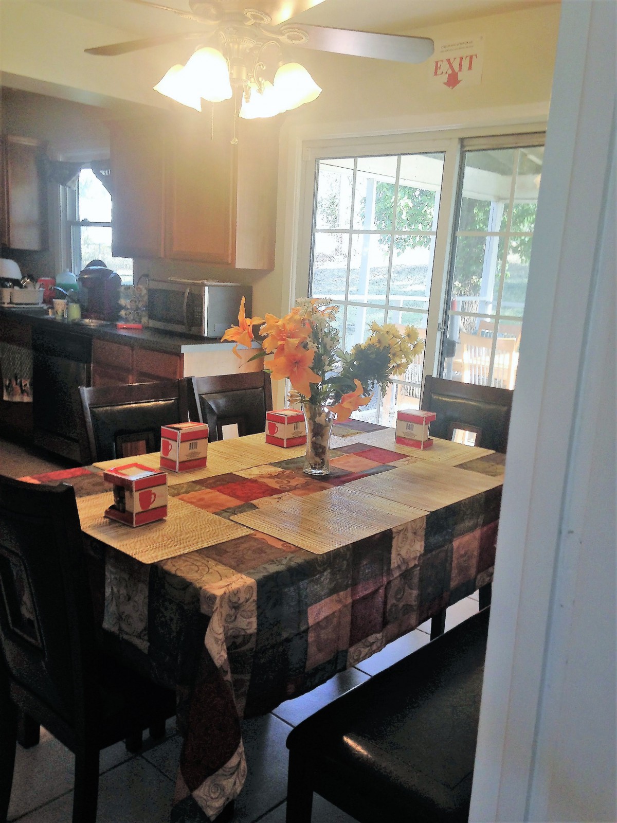 A cozy kitchen with a decorated dining table featuring flowers and a colorful tablecloth.