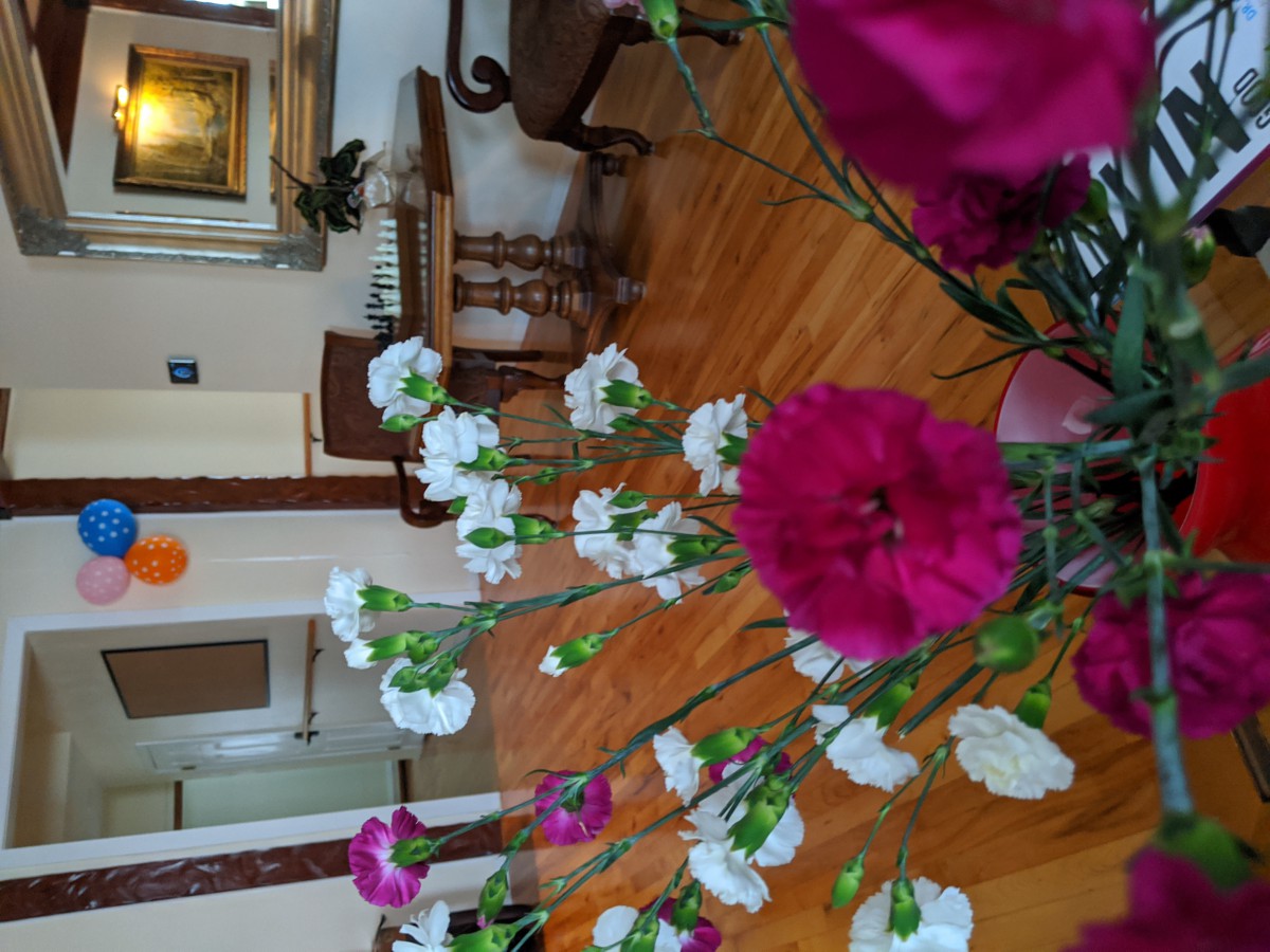 A vase of vibrant flowers decorates an elegantly furnished room with a wooden floor.
