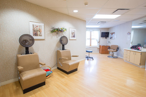 A spacious and modern waiting area in a hair salon, featuring comfortable seating and fans for customer comfort.