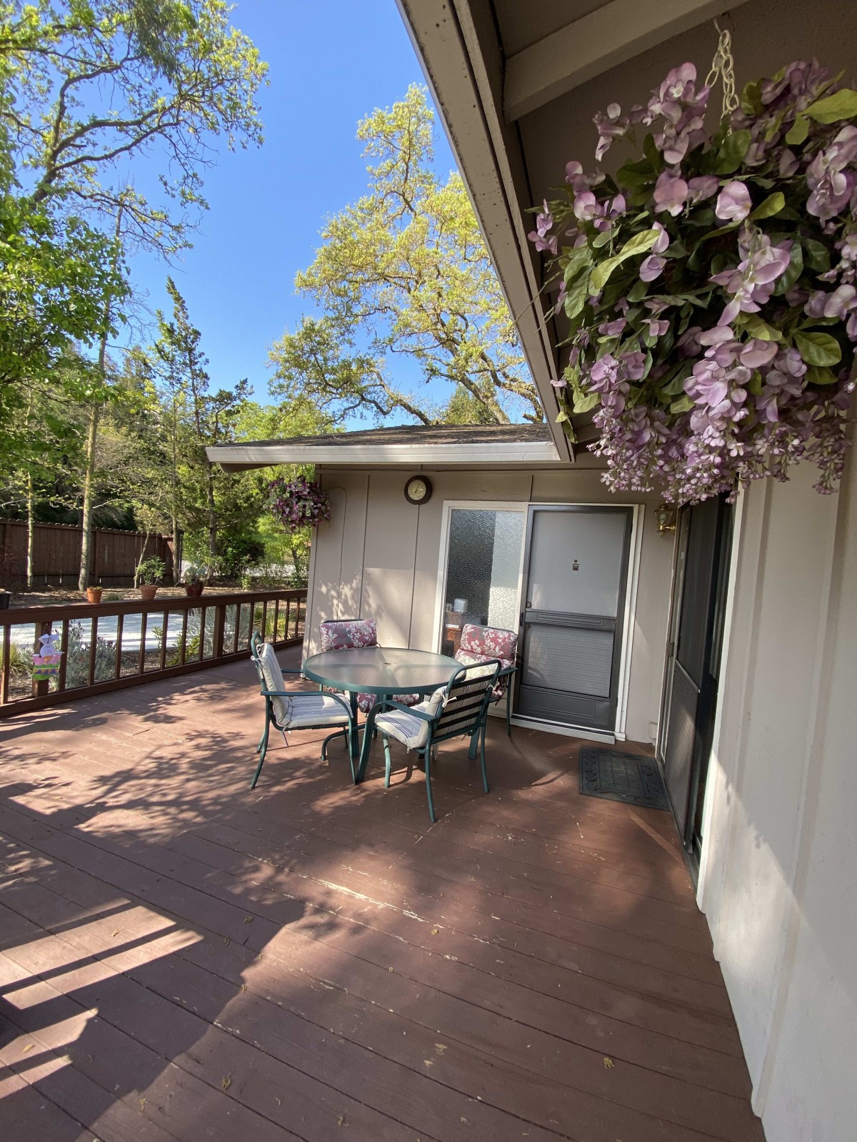 A sunny patio with a table and chairs surrounded by lush plants and flowers.