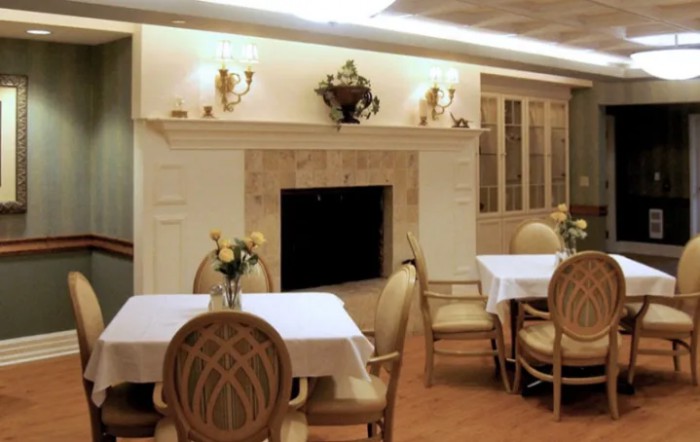 An elegant dining room with a fireplace and neatly arranged tables and chairs.