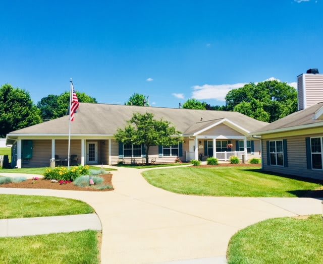 A residential building with a driveway and a well-maintained lawn on a clear day.
