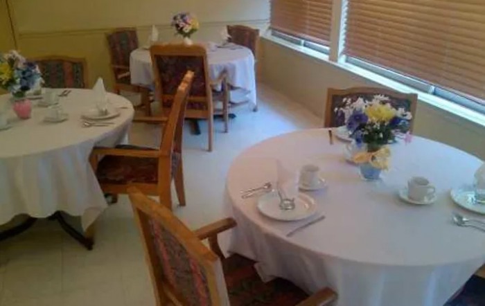 A cozy dining area set with tables, chairs, and floral arrangements.