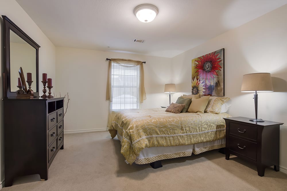 A cozy bedroom featuring a comfortable bed, artwork, and warm lighting.