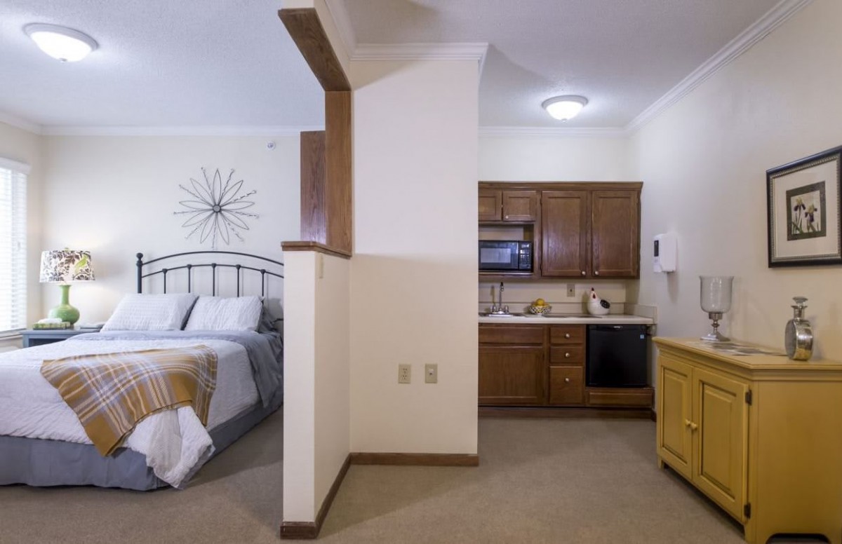 A cozy studio apartment with an open layout featuring a small kitchenette and a comfortable bedroom area.