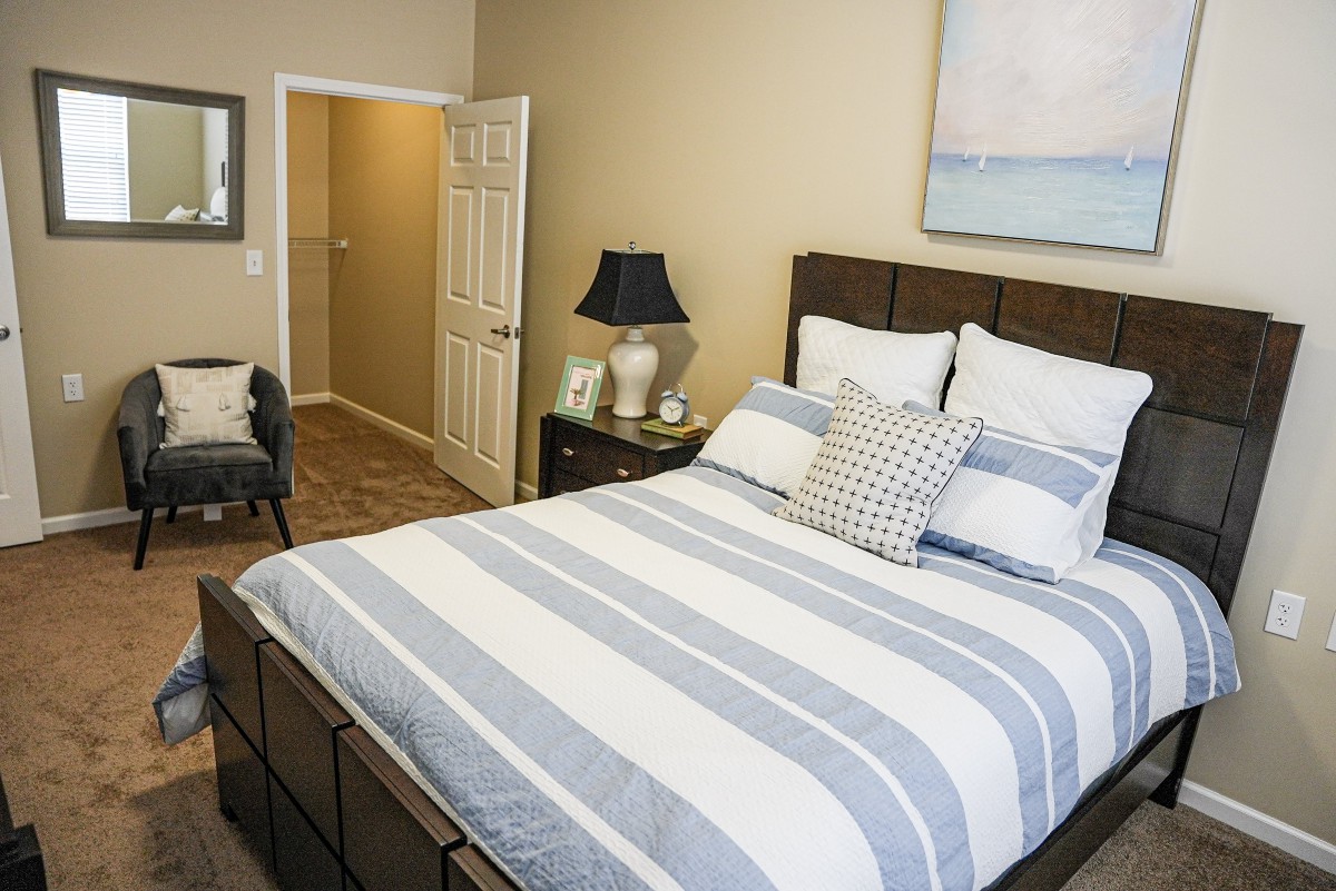 A cozy bedroom featuring a bed with striped bedding, a lamp, and modern decor.