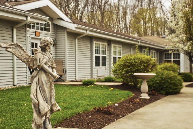 A well-maintained house with a garden and statue in the foreground.