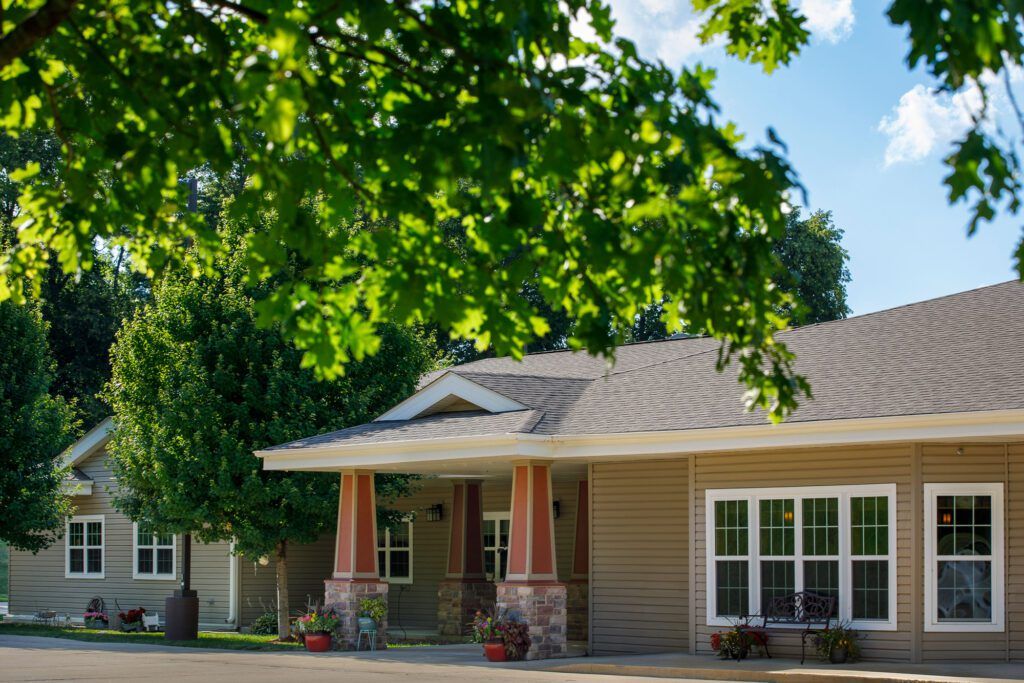 A cozy suburban house surrounded by lush greenery on a sunny day.