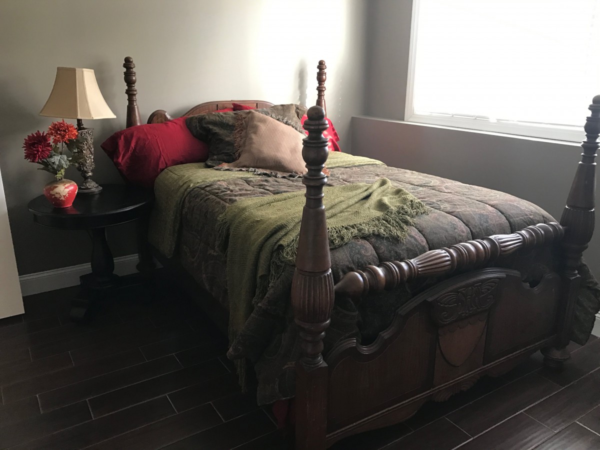 A cozy bedroom with a wooden four-poster bed and decorative pillows.
