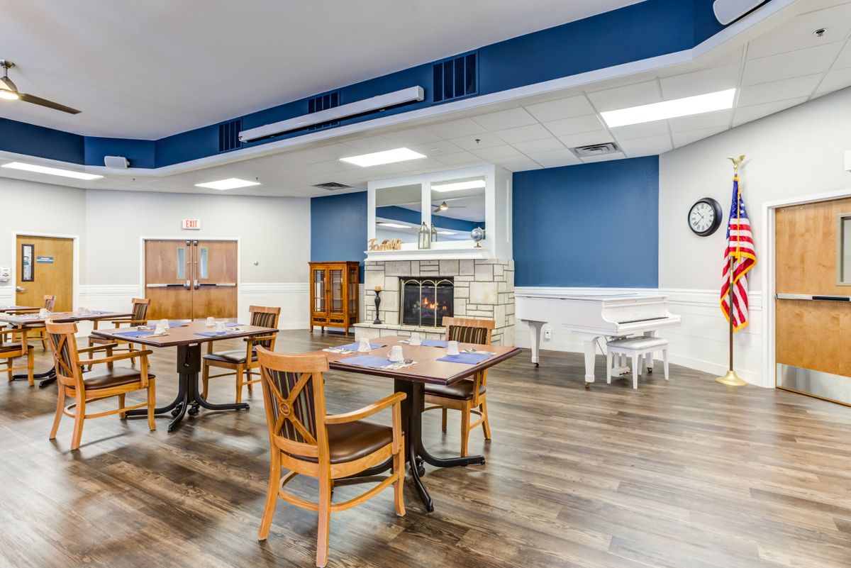A spacious dining area with wooden tables and chairs, featuring a fireplace and blue accent walls.