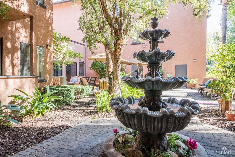 A serene courtyard with a multi-tiered fountain surrounded by trees and a cozy seating area.