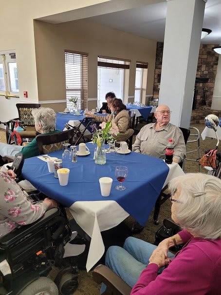 A group of elderly individuals seated around a table enjoying a social gathering indoors.