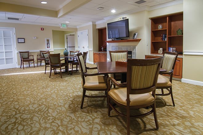 A cozy dining area with tables and chairs, featuring a television on the wall.