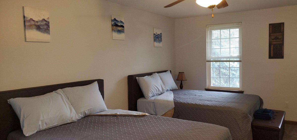 A cozy bedroom with two beds, a window, and decorative wall art.