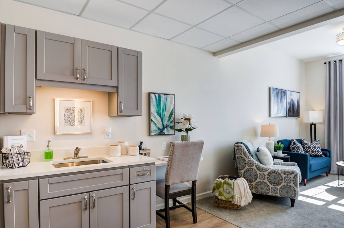 A modern office space with a desk, chair, and kitchenette, accented by colorful artwork on the walls.
