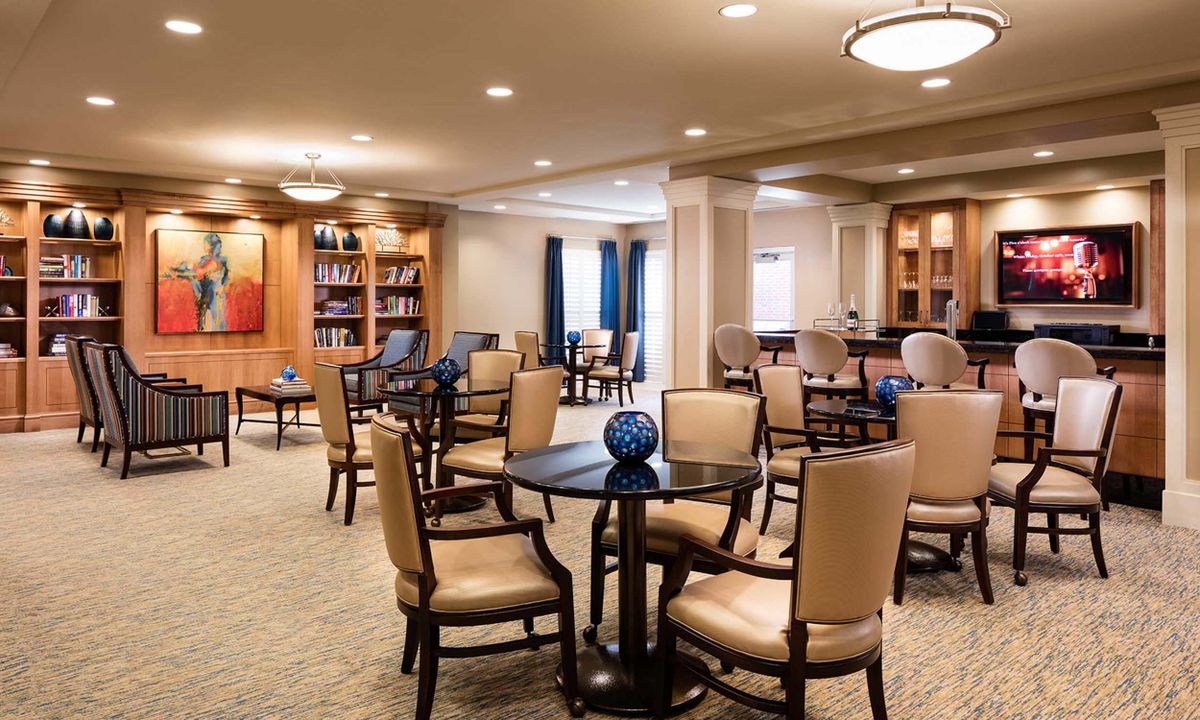 A cozy interior space with tables, chairs, and bookshelves, ideal for reading or relaxing.