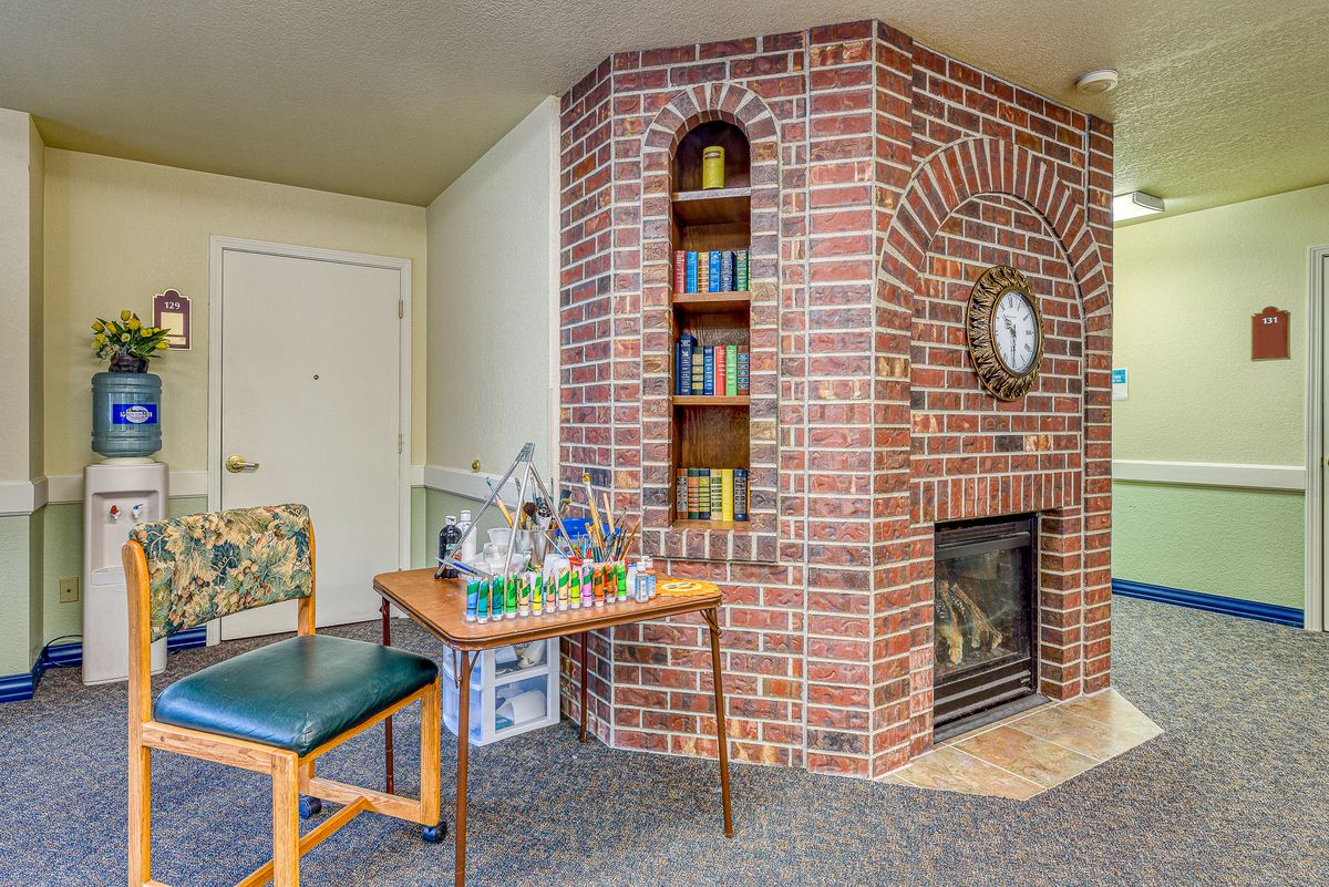 A cozy living room corner featuring a brick fireplace with an inbuilt bookshelf, a small table, and a chair.