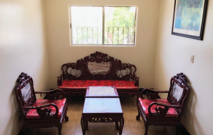 A traditional wooden sofa set with red cushions, accompanied by a matching coffee table, placed in a well-lit living room.