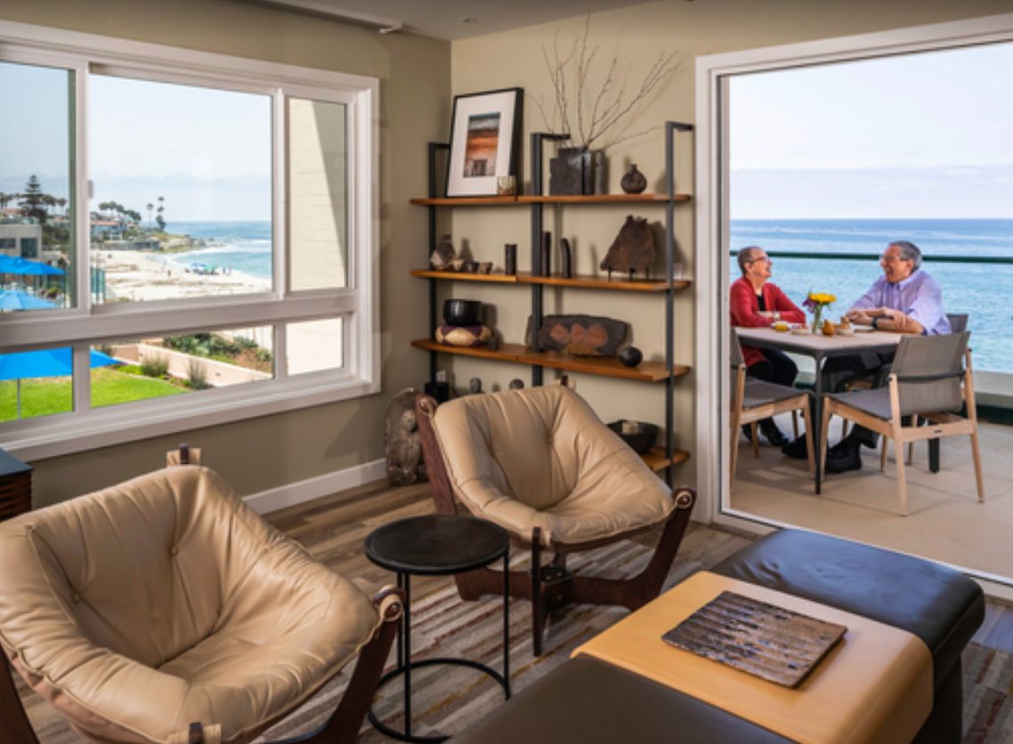 A cozy living room with modern furniture and a beautiful ocean view, leading to a balcony.