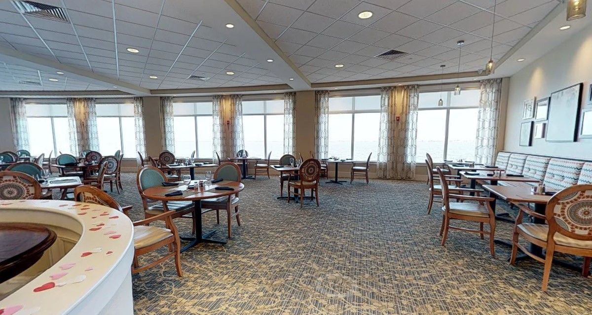 A spacious dining area with large windows and wooden furniture.