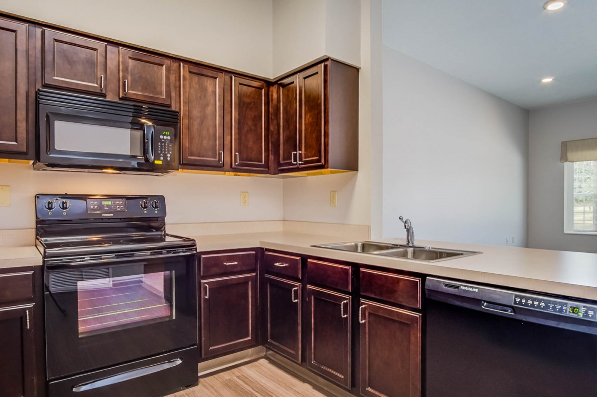 Modern kitchen with dark wood cabinets and appliances.