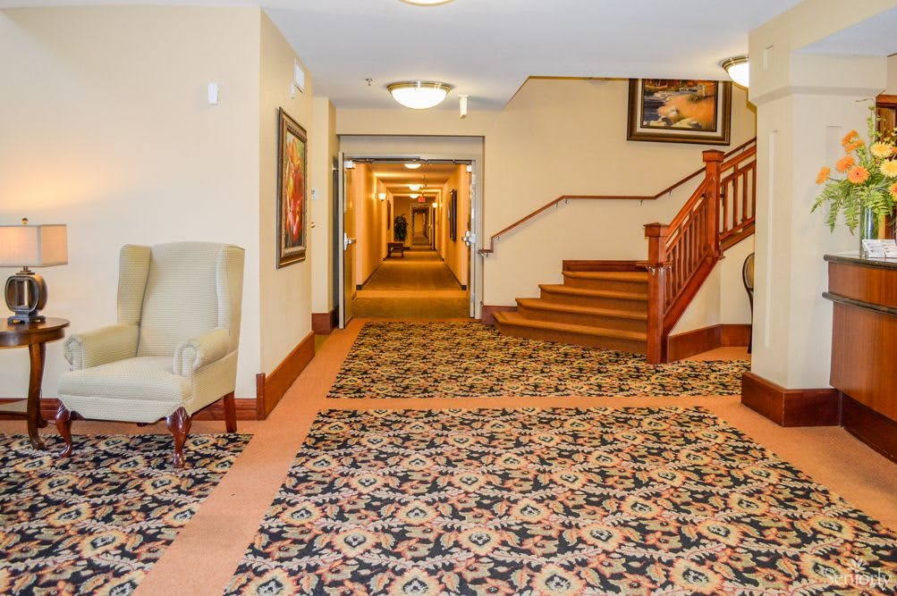 A hotel hallway with patterned carpet and a staircase.