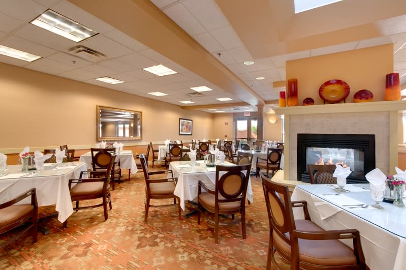 An inviting restaurant dining area with neatly arranged tables, elegant chairs, and a cozy fireplace.