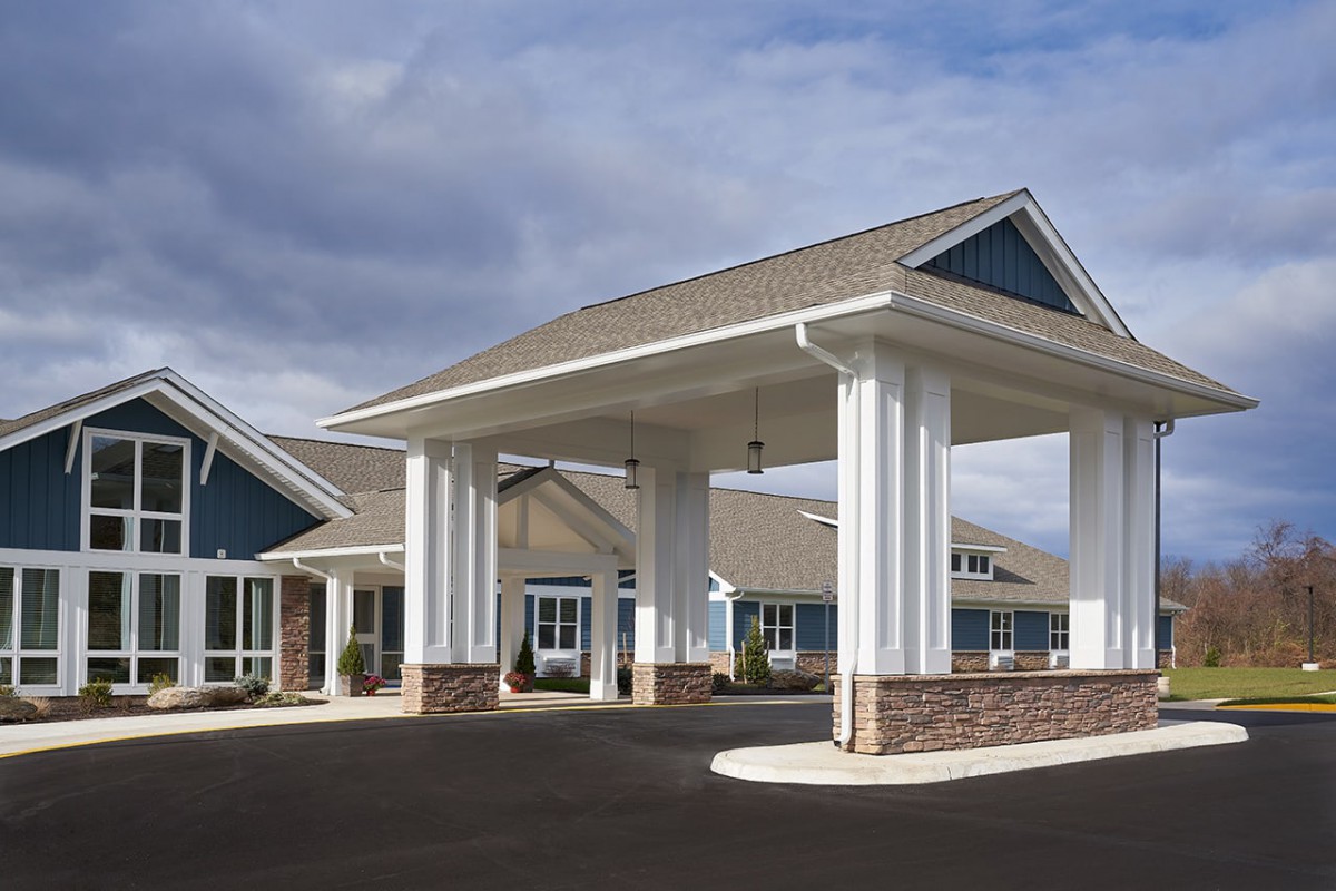 A modern building with a grand entrance featuring white columns and a sloped roof.