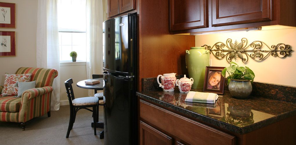 A modern kitchen with dark wood cabinets, a black refrigerator, and decorative items on the countertop.
