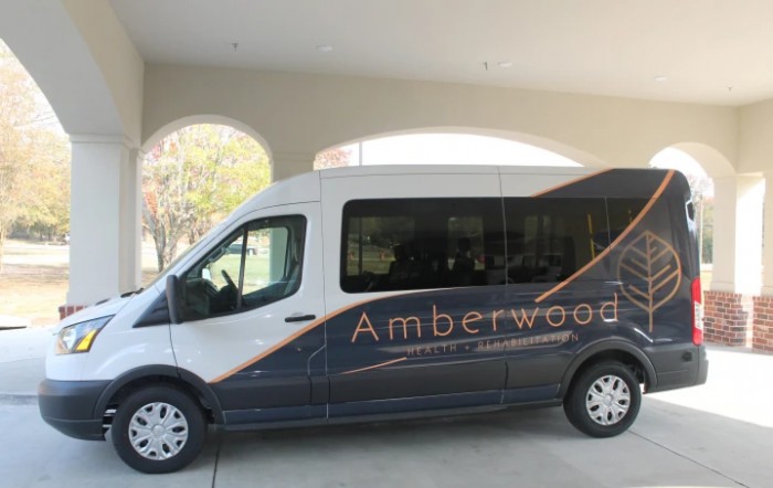 A van with the Amberwood logo parked under a covered area.