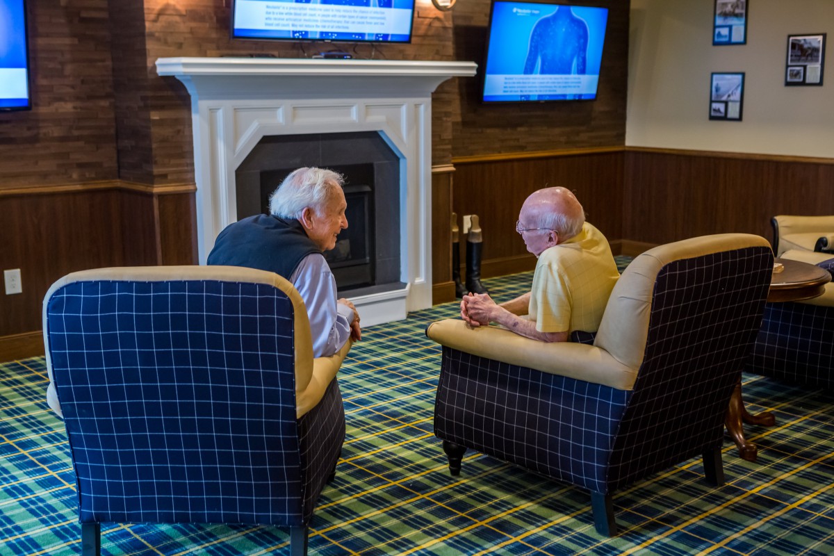 Two elderly men engaged in conversation while seated in a cozy indoor setting.