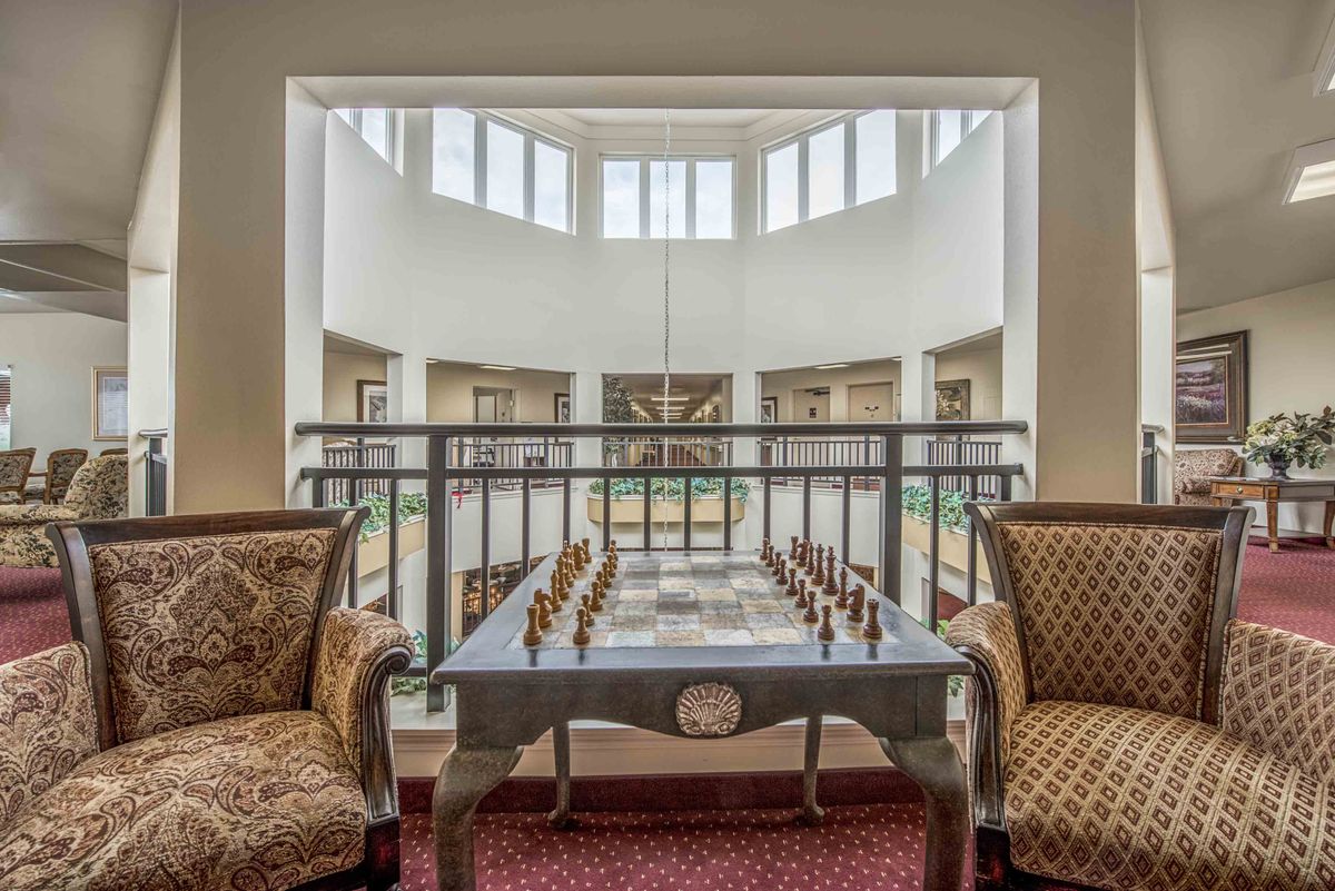 A luxurious lounge area featuring a chess table and comfortable chairs by large windows.