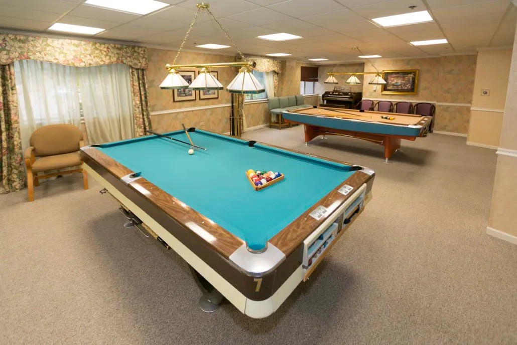 A recreation room featuring multiple pool tables and well-lit playing areas.