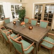 A well-furnished dining room with a rectangular wooden table surrounded by chairs, adorned with decorative items.