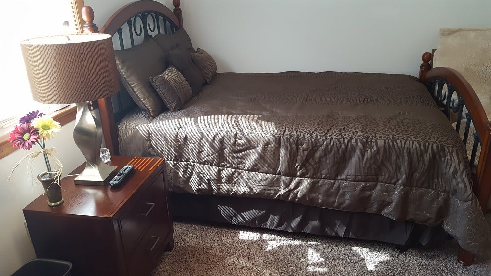 A cozy bedroom with a neatly made bed and a nightstand.